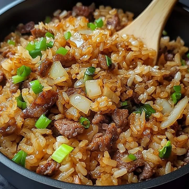 Delicious onion beef fried rice served in a bowl with fresh ingredients.